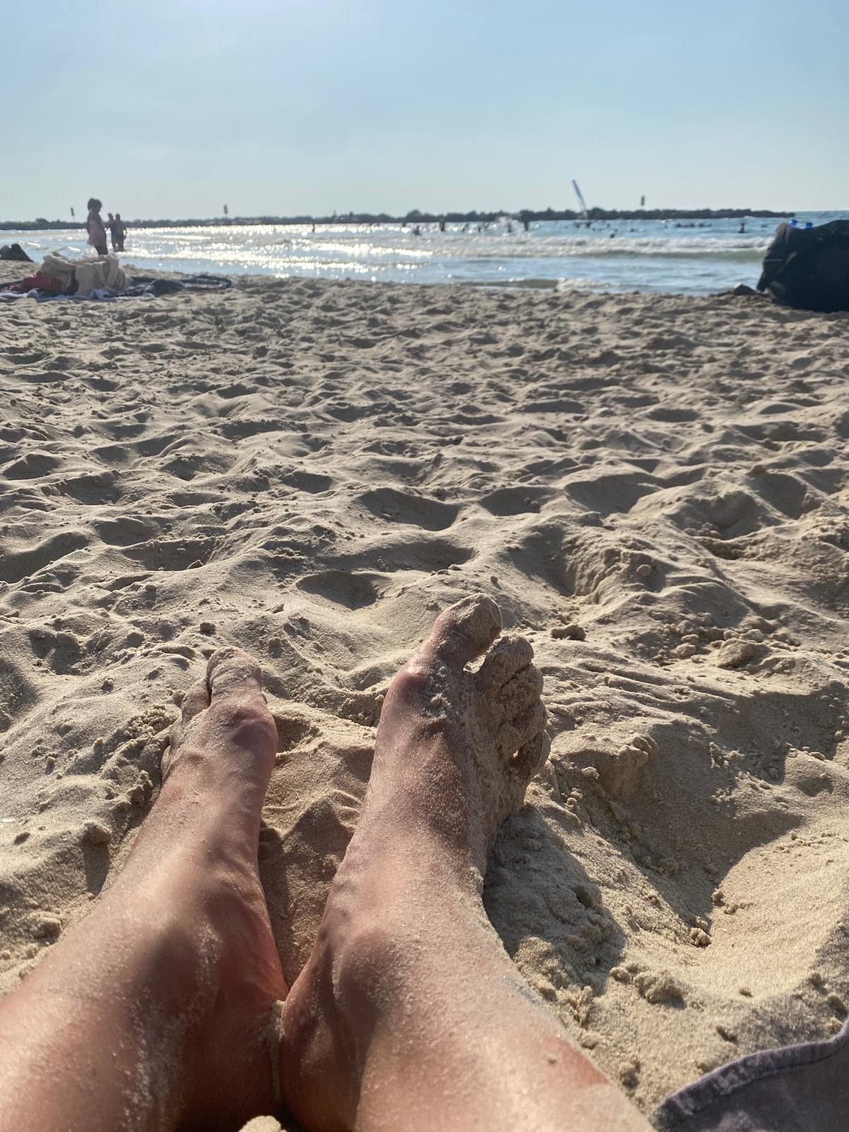 תמונה של כפות הרגליים בחול בחוף ים